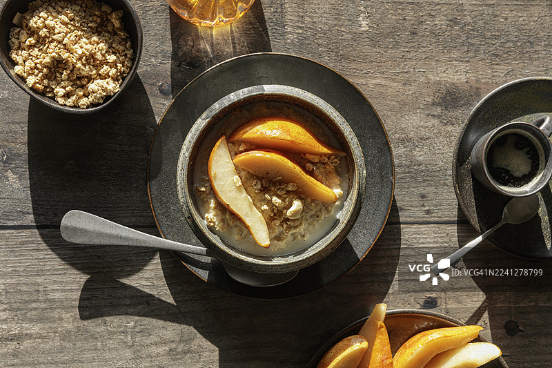 工作室灯光下，木桌上的纯素梨粥配格兰诺拉麦片图片素材