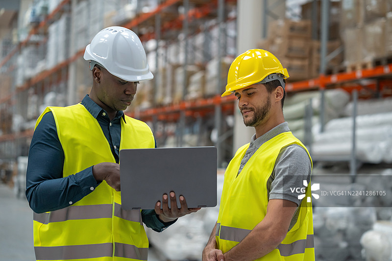 两位专业人士在仓库环境中讨论策略图片素材