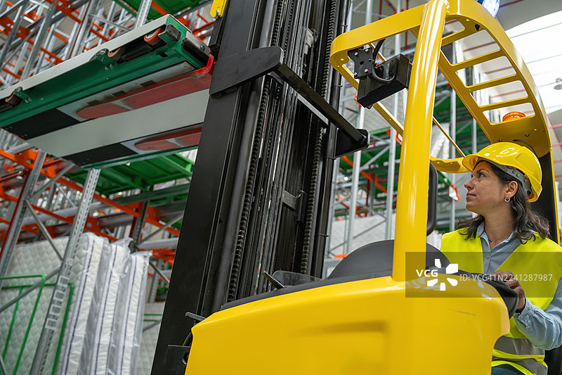 仓库工作人员在货架附近操作叉车图片素材