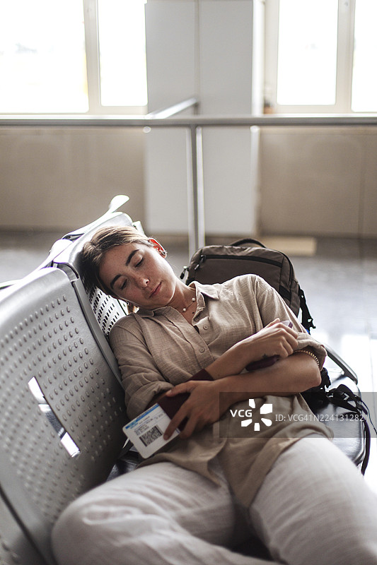 疲惫的旅客在机场航站楼睡着了，身边放着文件和背包图片素材