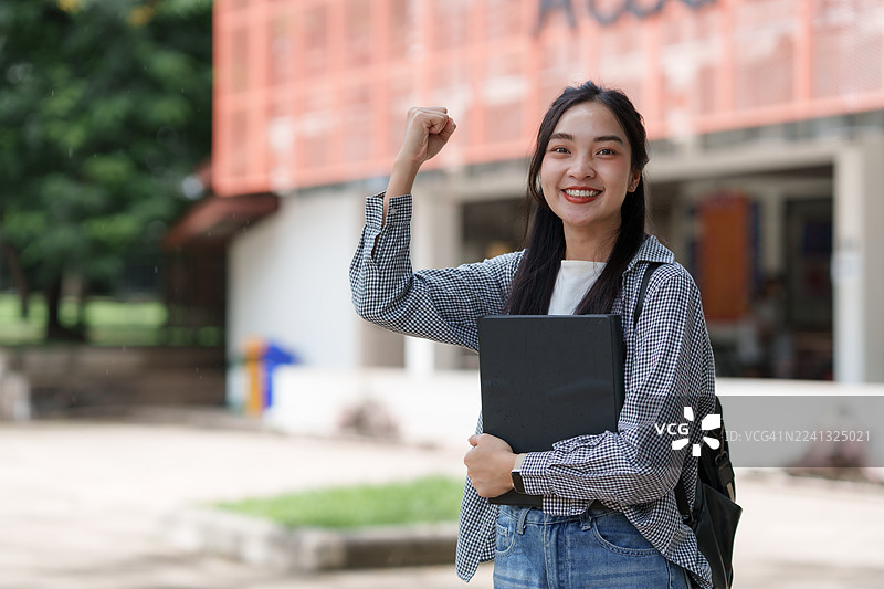年轻的亚洲女学生在校园里庆祝学业成功图片素材