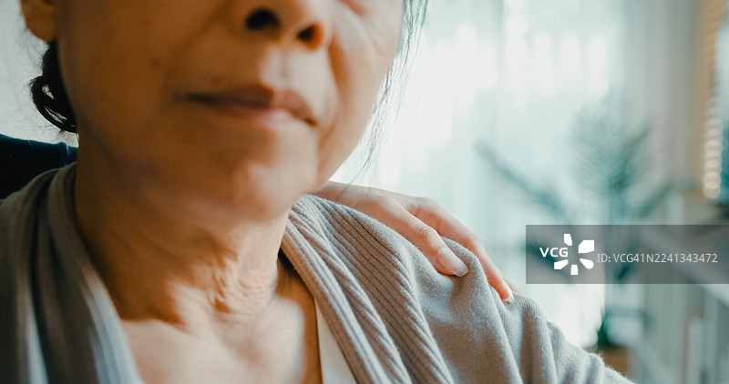 特写：年轻的亚洲护士在客厅安慰坐在轮椅上的老年妇女，提供情感支持和关怀。居家健康护理。图片素材