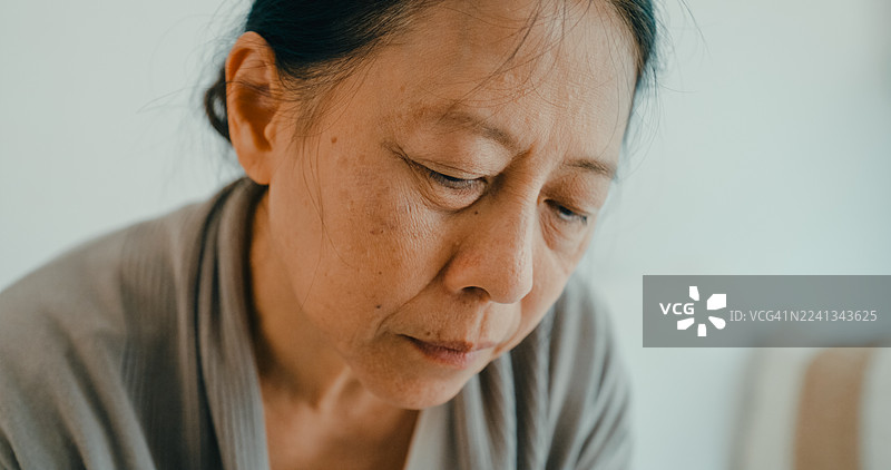 特写：年轻的亚洲护士在客厅的沙发上安慰一位年长的女士，提供情感支持和关怀。居家养老护理。图片素材