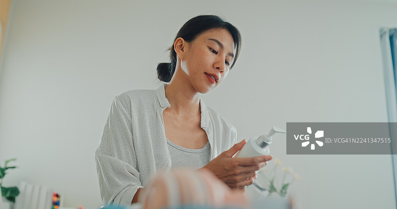 特写：年轻的亚洲女性在卧室的床上打包行李箱，为在家中舒适的夏日假期旅行准备衣物和个人物品。图片素材