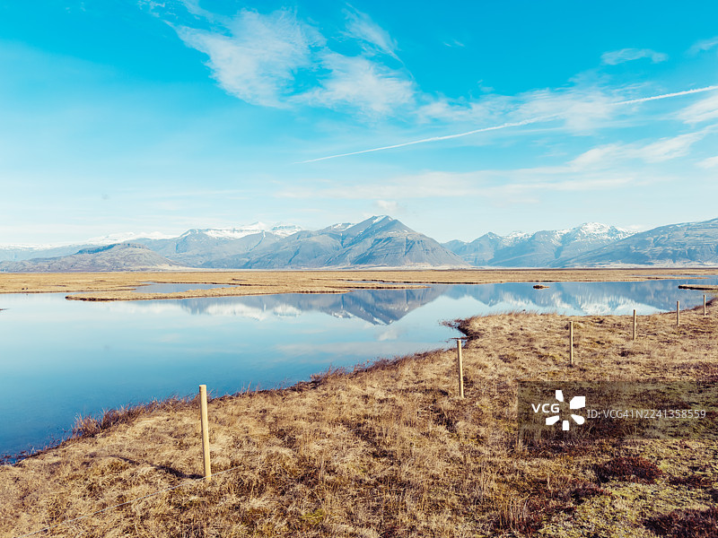冰岛南部海岸，小沼泽湖倒映着远处的雪山图片素材