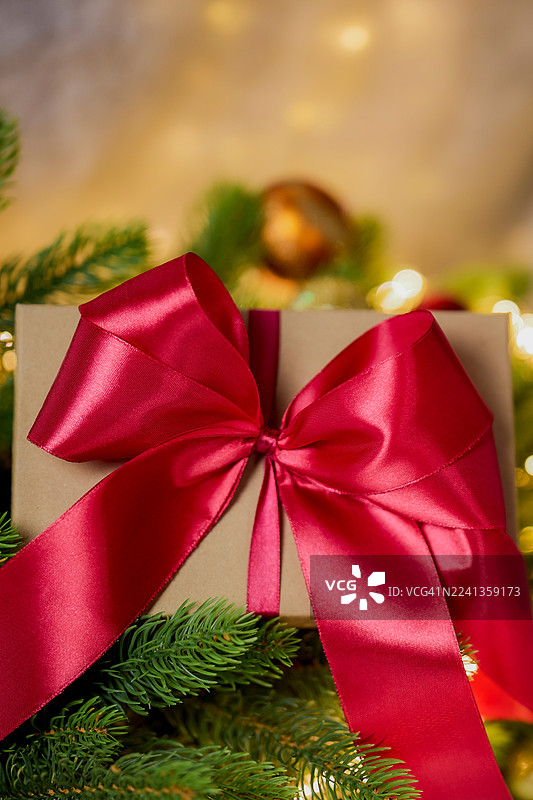 节日礼盒，系着红色丝带，置于绿色松枝之间，营造节日装饰和圣诞欢乐气氛图片素材