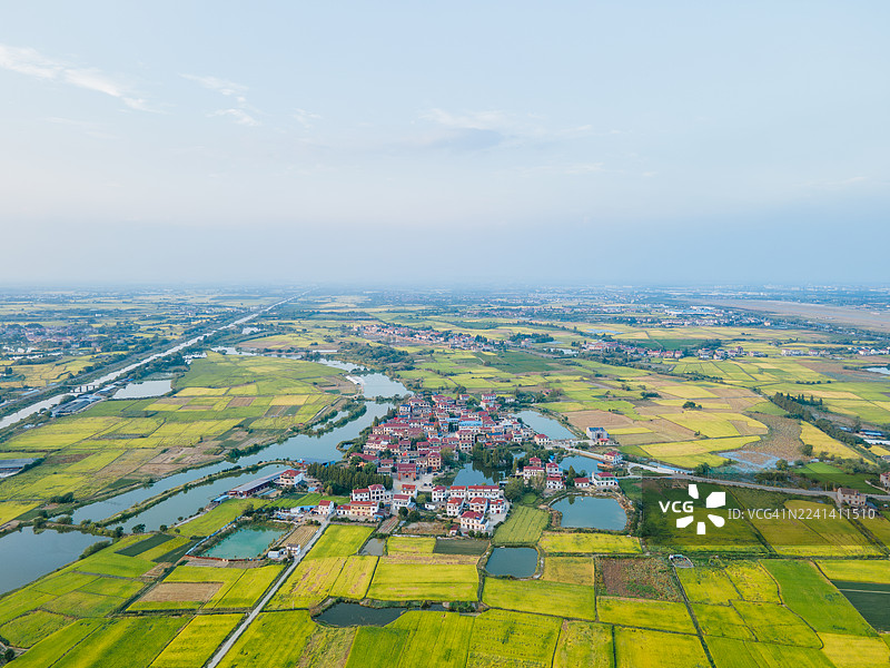 日落时分，空中俯瞰一条穿过耕地的公路，金色的阳光将长长的影子投射在田野上。风景如画的乡村景观，展示了现代交通与农业的和谐共处，象征着进步、自然，图片素材