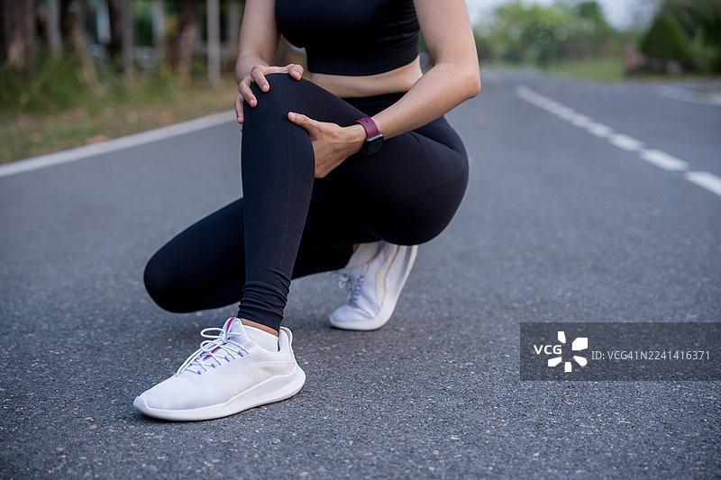 膝盖疼痛。运动损伤，一名女性在户外运动时膝盖疼痛。跑步运动中女性跑者的膝盖损伤。图片素材