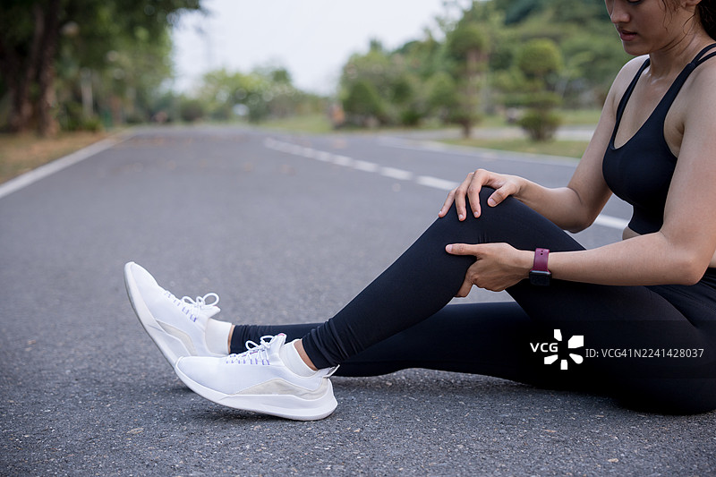 膝盖疼痛。运动损伤，女性在户外运动时膝盖疼痛。跑步运动对女性跑者的膝盖损伤。图片素材