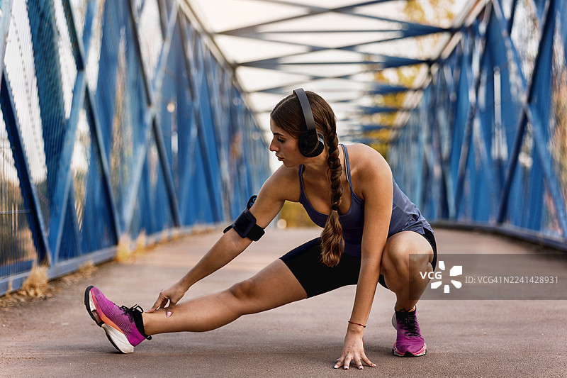 女人在锻炼前在桥上伸展图片素材
