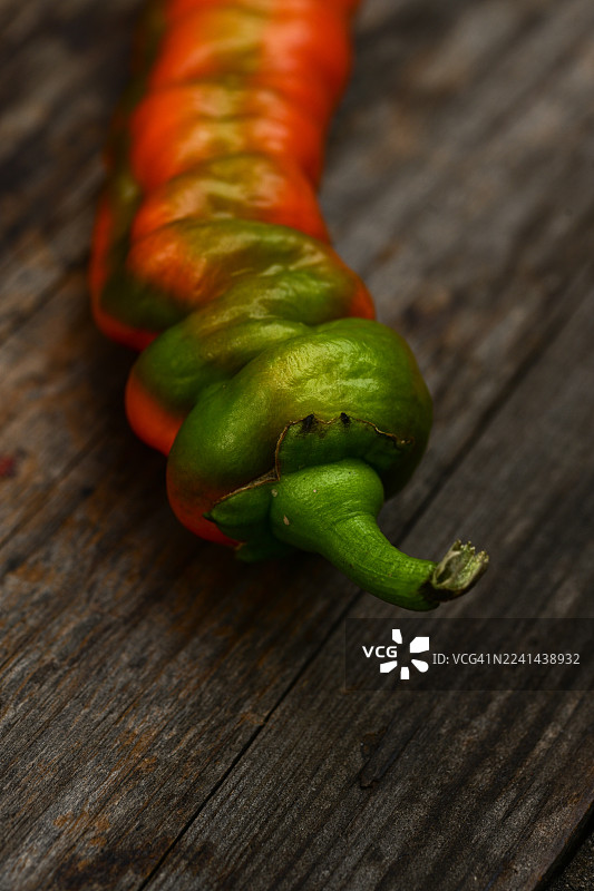 充满活力的绿色和橙色辣椒特写，放置在质朴的木质表面上图片素材