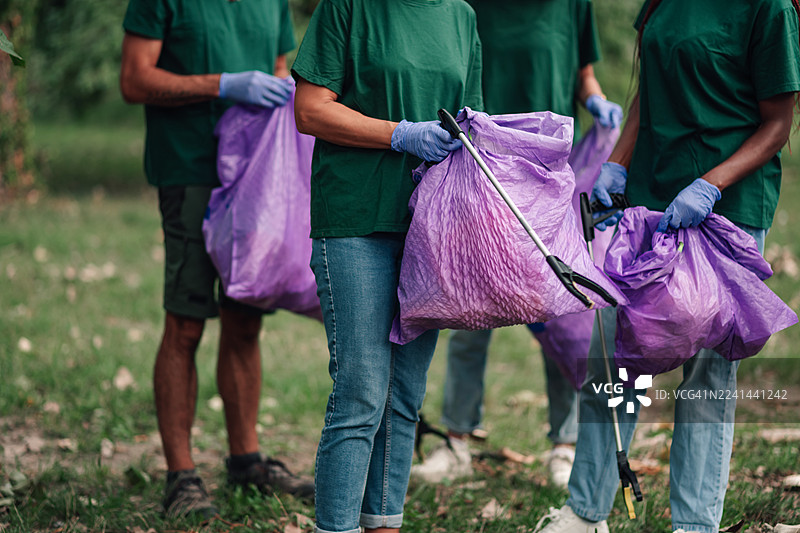 志愿者使用夹子捡拾垃圾，清理公园图片素材