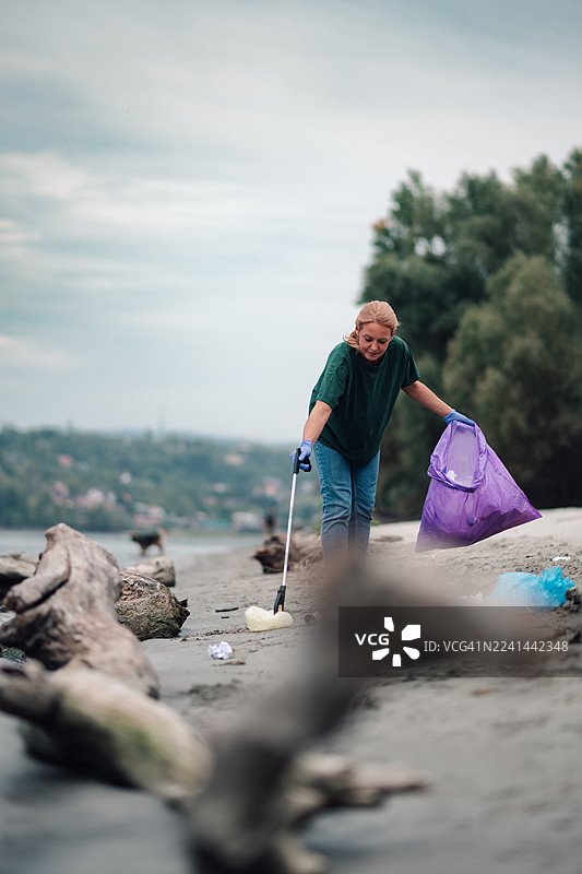 女子在被污染的海滩上收集塑料垃圾图片素材