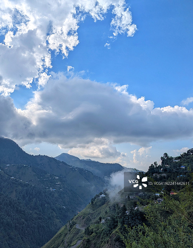 雄伟的山脉和郁郁葱葱的绿色山谷笼罩在雾中，天空布满戏剧性的云彩图片素材