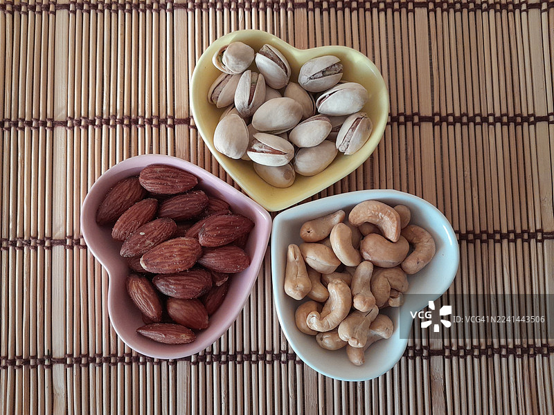 竹席上心形碗里盛着各种坚果的俯拍图图片素材