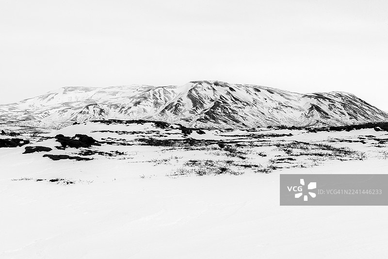 冰岛塞爾福斯，冰雪覆盖的山脉和火山地貌在严酷天空下的戏剧性黑白风光图片素材