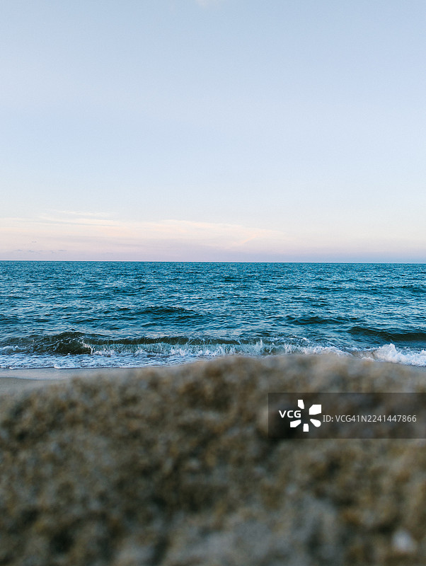 晴朗天空下的广阔蓝色大海的风景，前景是沙滩图片素材