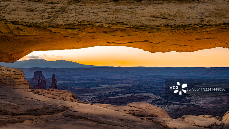 美国梅萨拱门，戏剧性的日落笼罩着广阔的沙漠景观，奇特的岩石构造在天然拱门中构成画面。图片素材