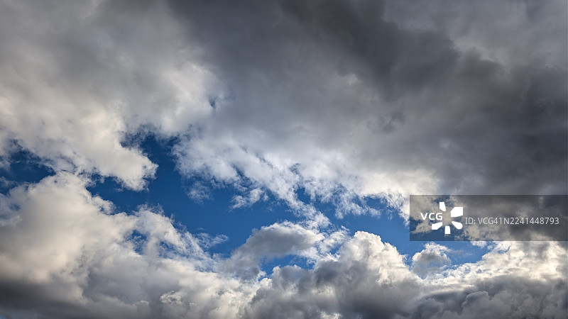 蓝色天空下的戏剧性低角度云彩景观，展现了大气的浩瀚与瞬息万变图片素材