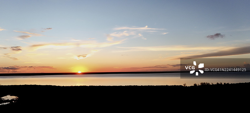 宁静的湖面，水面如镜，倒映着壮丽的日落景色图片素材