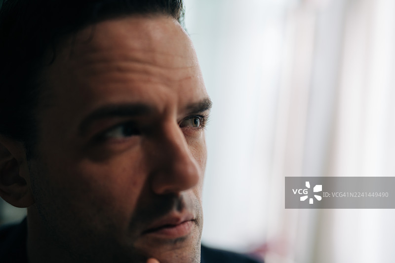 光线柔和，成年男子若有所思地凝视远方图片素材