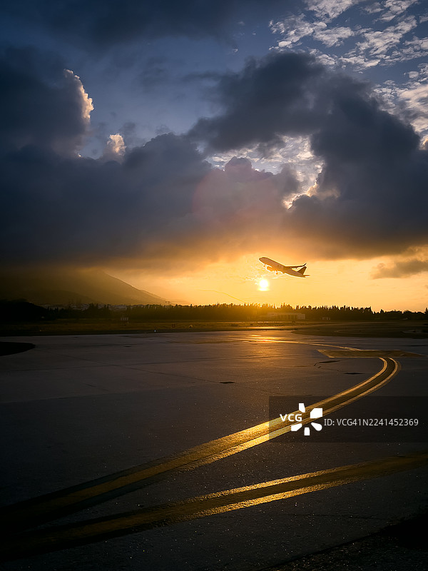 日落时分，飞机起飞，伴有戏剧性的云彩。图片素材