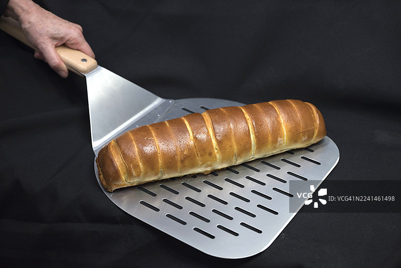 新鲜出炉的委内瑞拉火腿面包，用烘焙金属铲托着图片素材