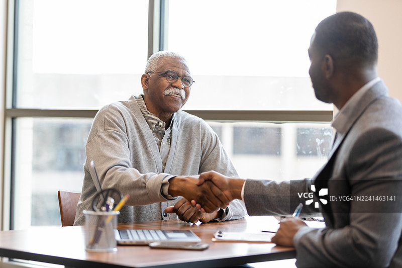 两位商务人士在专业的办公室环境中握手并达成交易。图片素材