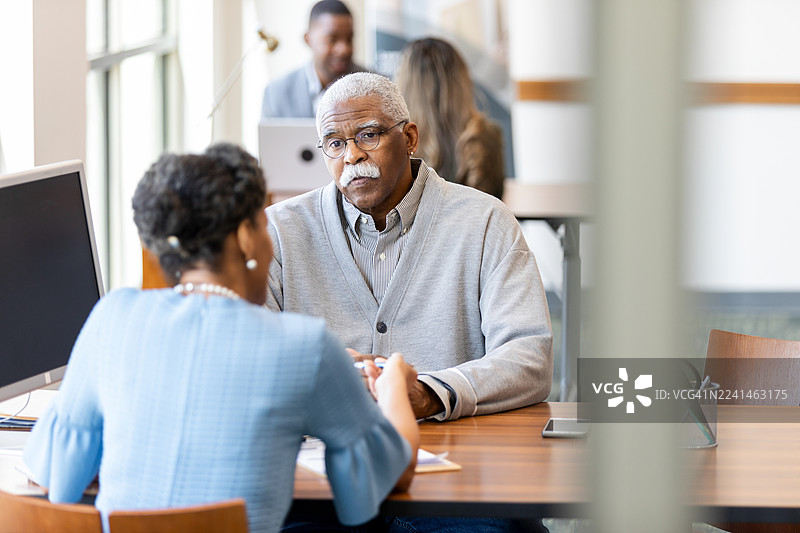 老年夫妇在会议上讨论重要事项，展现出协作与专业精神。图片素材