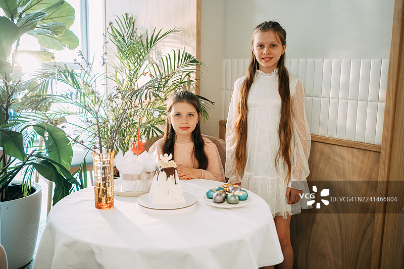 两个女孩在庆祝复活节，有传统的蛋糕和彩蛋。图片素材