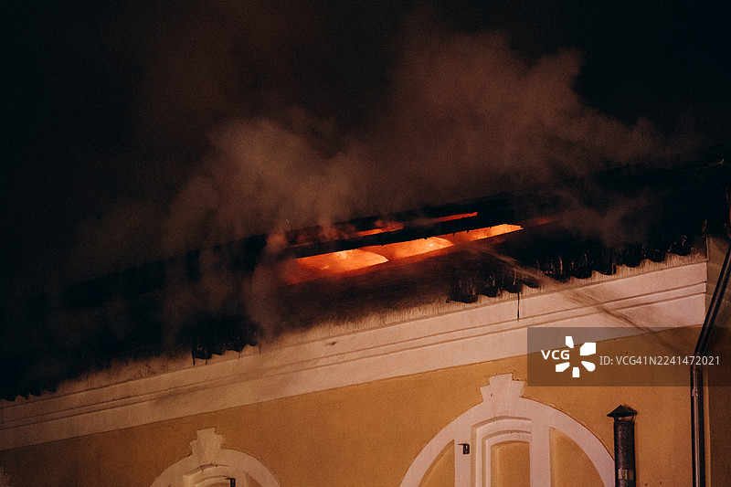 夜晚，建筑物屋顶燃起熊熊大火，浓烟滚滚。图片素材