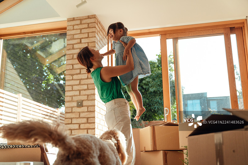 一位年轻的亚洲母亲和她的女儿兴奋地搬进新家图片素材