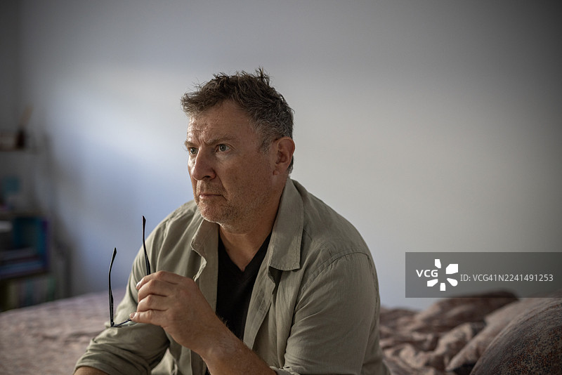 肥胖的男人情绪低落，坐在床上图片素材