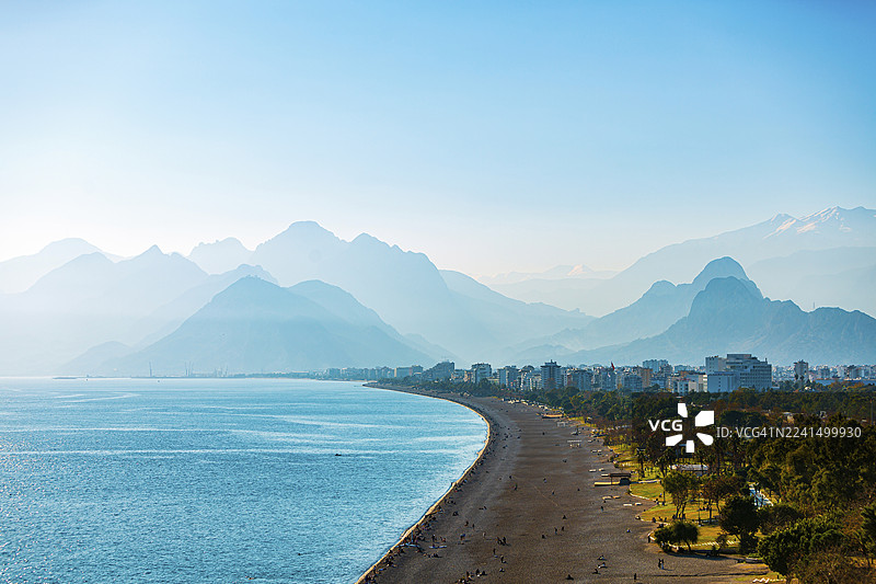十二月安塔利亚科尼亚尔蒂海滩——日落时分的滨海城市与山峦图片素材