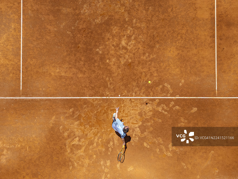专业网球运动员在红土场上发球，航拍视角图片素材