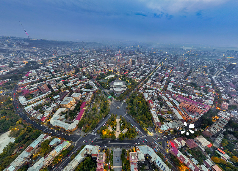 亚美尼亚埃里温卡斯卡德综合体的壮观鸟瞰双联画，展示了其宏伟的建筑图案和日落时分闪耀的城市灯光。图片素材