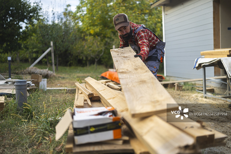 白天在户外建造木屋的胡子男木匠图片素材