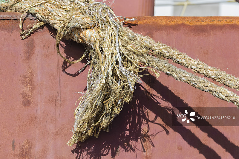 一根饱经风霜的船用绳索从船舷斜挂下来图片素材