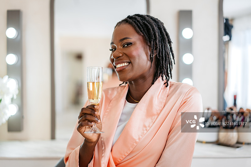 妆容精致的年轻黑人女性在美容院饮用香槟图片素材