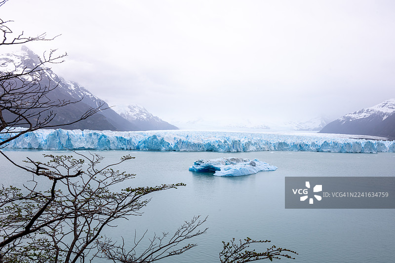 雪山冰川背景下，阴云密布的天空映衬着冰封的湖面，景色壮丽。图片素材