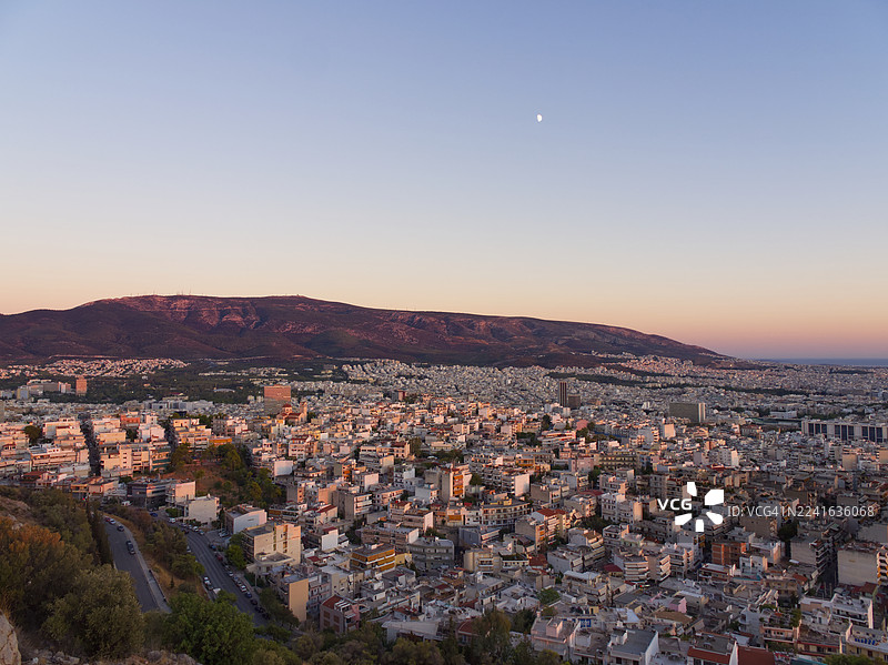 日落时分，高角度俯瞰城镇景观，建筑与山峦倒映在晴朗的天空中。图片素材