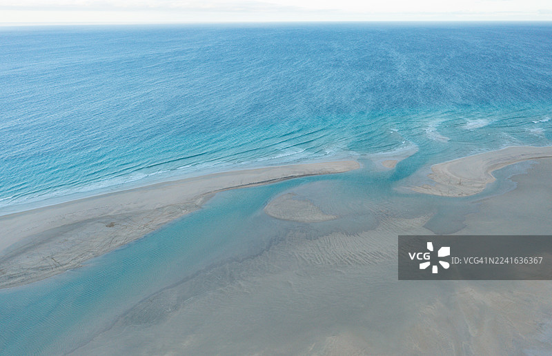 清澈天空下的海面和沙质海岸的鸟瞰图，展示了自然纹理和美丽的蓝色海水图片素材