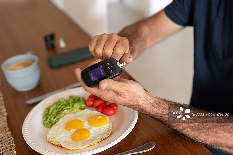 一位中年西班牙裔糖尿病患者在家中测量血糖水平图片素材