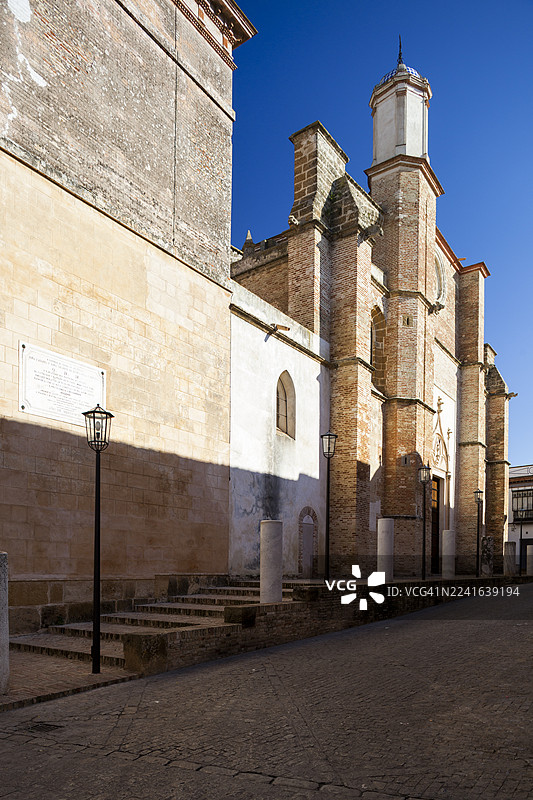 从低角度拍摄的一座古老历史建筑，背景是晴朗的蓝天，展示了建筑细节和鹅卵石街道，地点：西班牙卡尔莫纳图片素材