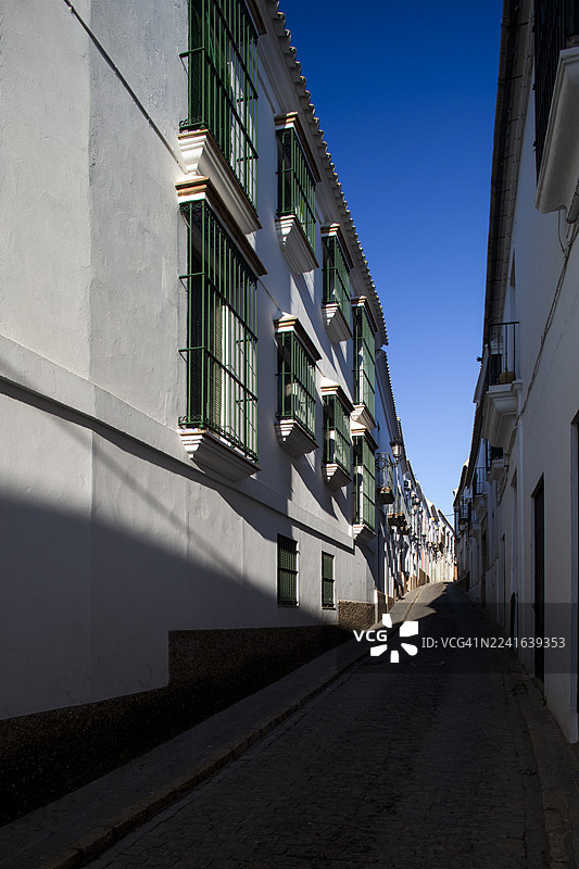 晴朗蓝天下，带有白色建筑的狭窄街道，投下长长的阴影，西班牙卡蒙纳图片素材