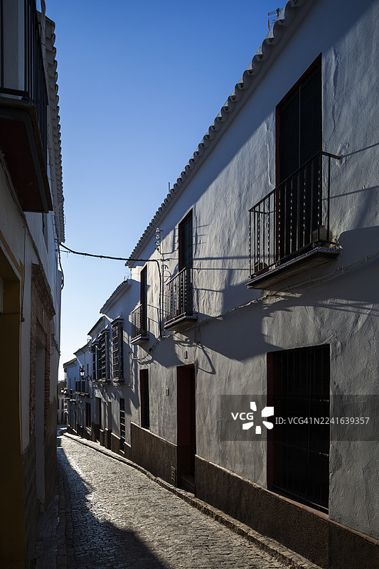 蓝天白云下，白色建筑与阳台环绕的空旷巷道，散发着历史的韵味与宁静的孤寂，西班牙卡莫纳图片素材