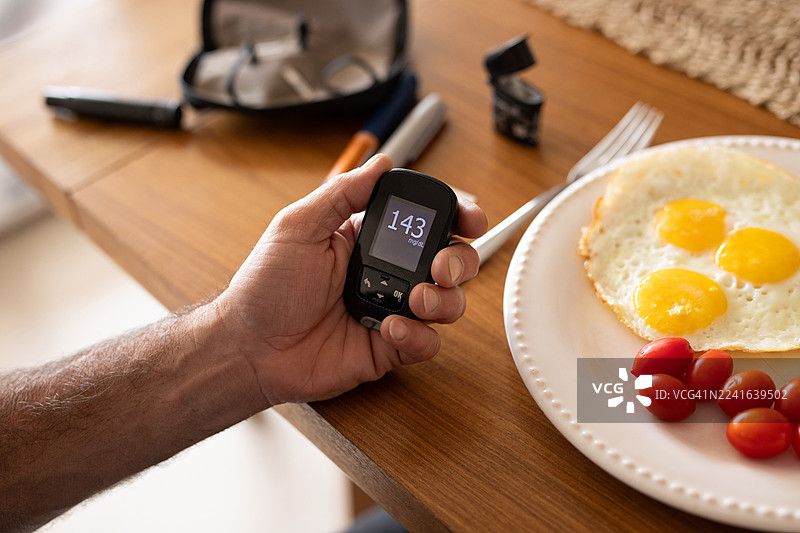 一位患有糖尿病的成熟西班牙裔男性在家中测量血糖水平图片素材