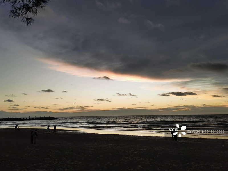 马来西亚美里，夕阳下的海滩剪影，天空壮丽，海浪翻涌图片素材
