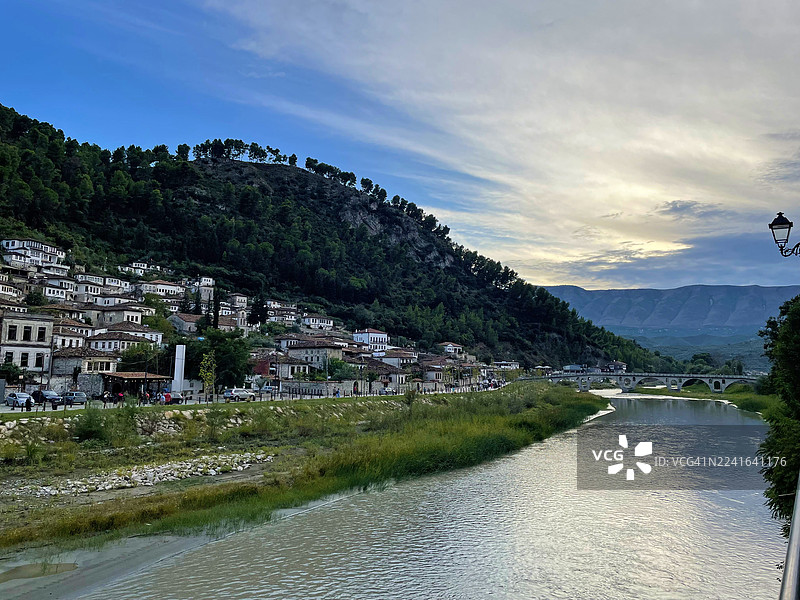 阿尔巴尼亚培拉特，历史建筑依偎在山坡上，俯瞰着宁静的河流，天空动感十足图片素材