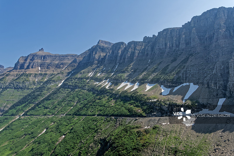 白雪皑皑，绿草茵茵的山脉在湛蓝的天空下显得雄伟壮丽，展现了大自然的壮丽景色图片素材